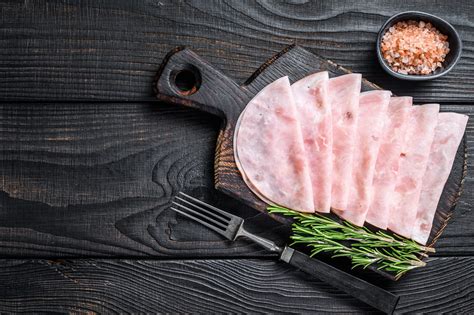 Čerstvá domáca šunka na drevenej doske s bylinkami