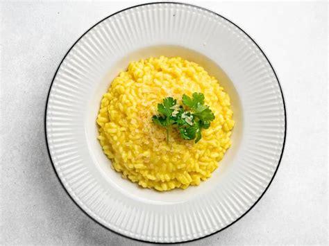 Servírované risotto alla milanese s pohárom bieleho vína