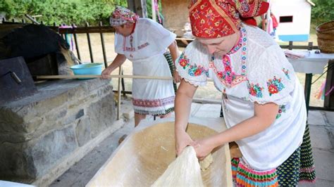 Ľudia mlátiaci obilie cepami v tradičnom dvore