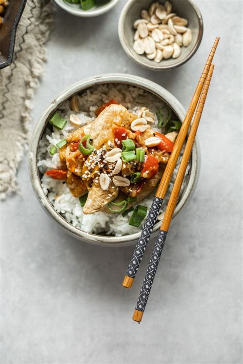 Miska s kuracím Kung Pao, ryžou a posypaná arašidmi a jarnou cibuľkou.