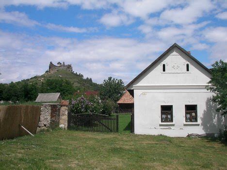 Starý slovenský dedinský dom, pred ktorým sa v noci pri ohni zhromažďujú ľudia a počúvajú rozprávača
