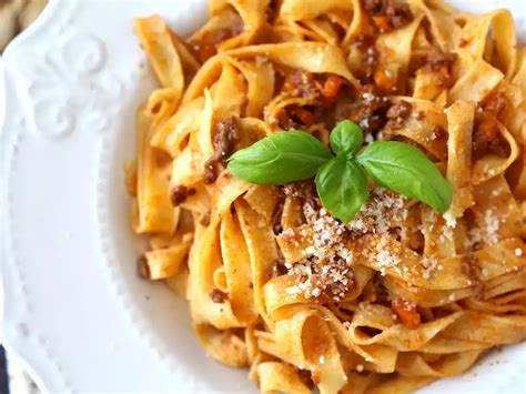 Fotografia taniera s tagliatelle a bolonskou omáčkou posypanou parmezánom