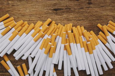 Osoba trpiaca kašľom, so siluetou cigarety v pozadí