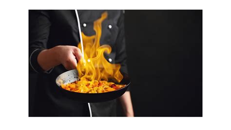 Kuchár flambuje pokrm pri stole pre hostí