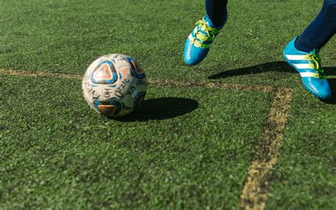 Futbalista na trávniku s loptou, v pozadí tabuľka s výživovými odporúčaniami