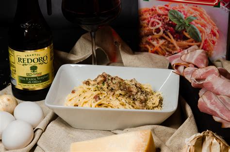 Taniere s čerstvými špagetami carbonara zdobené čiernym korením a syrom