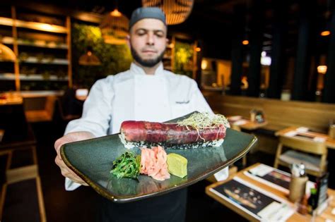 Sushi majster pri práci s ryžou a rybou