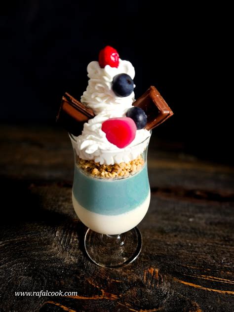 Fotografia trojvrstvovej panna cotty v pohári, posypanej kakaom a ozdobenej čerstvým ovocím.