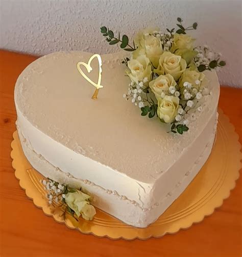 Biela svadobná torta so zlatými akcentmi a sviežimi kvetmi