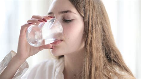 Osoba pijúca vodu a symboly hydratácie